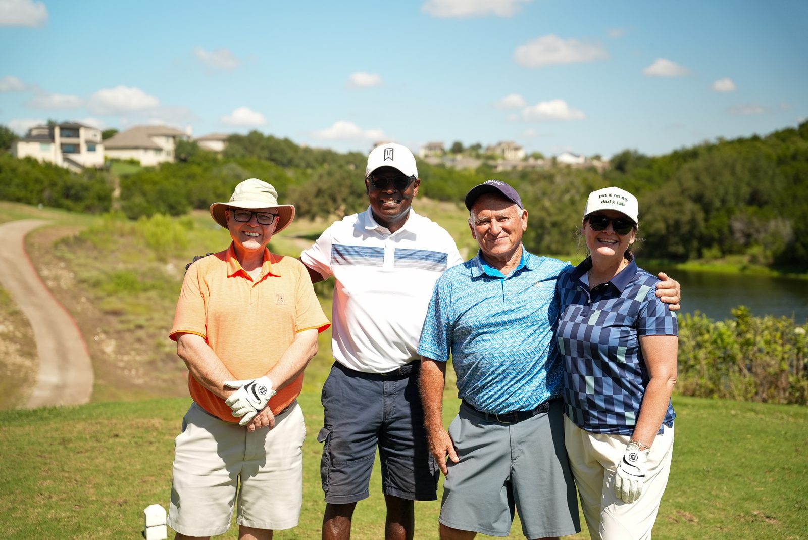 Four golfers with their arms around each other on the Hole 4 tee box